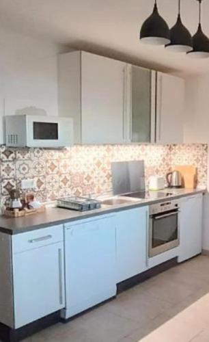 a kitchen with white cabinets and a stove at Olcsica Apartment in Klenovica