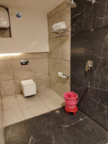 a bathroom with a shower with a red bucket at Kuyal Corbett Resort in Rāmnagar