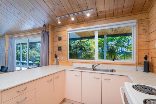 a kitchen with a sink and a large window at Sea Breezes in Matarangi