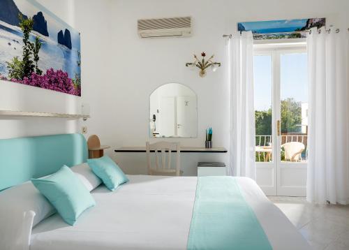 a white bedroom with a bed and a balcony at Hotel Carmencita in Anacapri