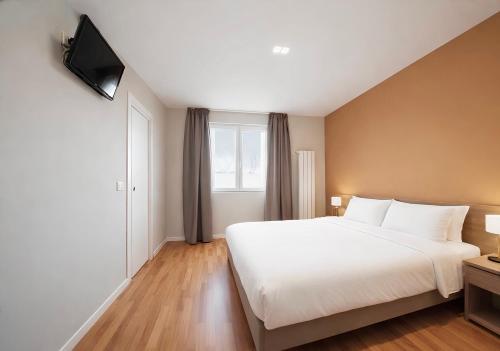 a bedroom with a white bed and a television at Foresteria Via Italia - Rooms & Suite in Rho