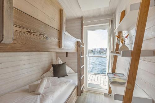a small bedroom with a bunk bed and a window at Hausboot "Mien Schipp" mit Sonnendeck im Yachthafen in Fehmarn
