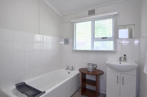 a white bathroom with a sink and a bath tub and a sink at Kommaweer in Yzerfontein