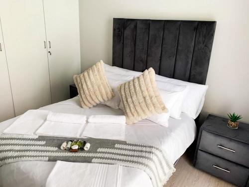 a bedroom with a bed with white sheets and pillows at Lekoa Lifestyle Apartment in Vanderbijlpark