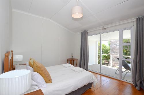 a bedroom with a white bed and a large window at Kommaweer in Yzerfontein
