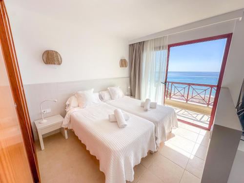 a bedroom with two beds and a view of the ocean at Prope Mare Apartamentos in Cala Millor