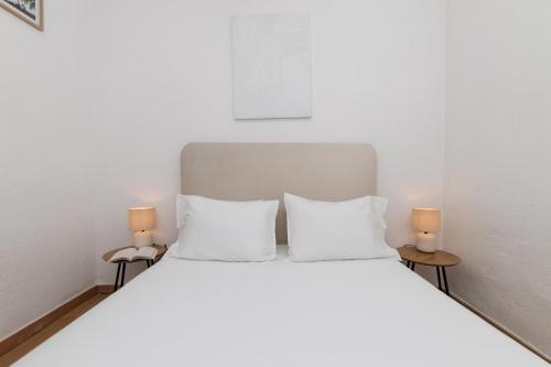 a white bed with two white pillows and two lamps at Peaceful Retreat near Sesimbra and Meco Beach - MADA HOUSE's II in Sesimbra