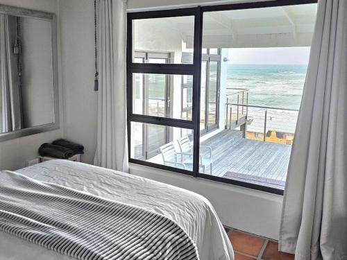 a bedroom with a large window with a view of the ocean at Ocean View Drive 150 in Struisbaai