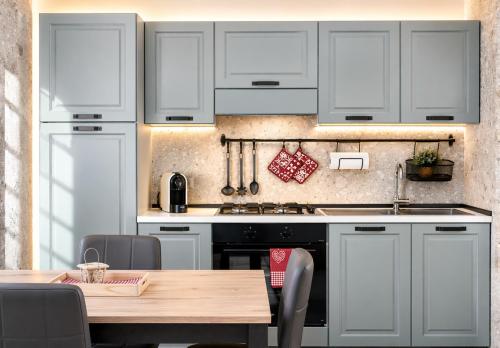 a kitchen with white cabinets and a wooden table at IL CERVO - 2 camere, garage Dolomiti Affitti in Cavalese