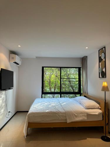 a bedroom with a large bed and a window at The Title Rawai in Ban Saiyuan (1)