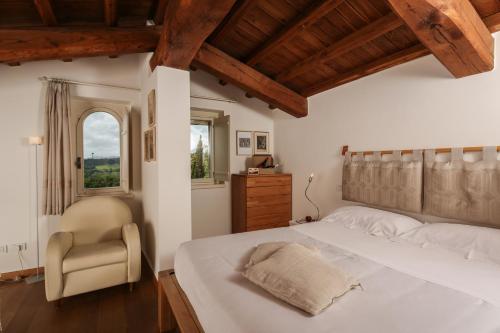 a bedroom with a bed and a chair and a window at Roccafiore Wine Resort & Spa in Todi