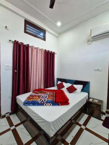 a bedroom with a bed with red curtains at Hotel Royal galaxy in Dharāsu