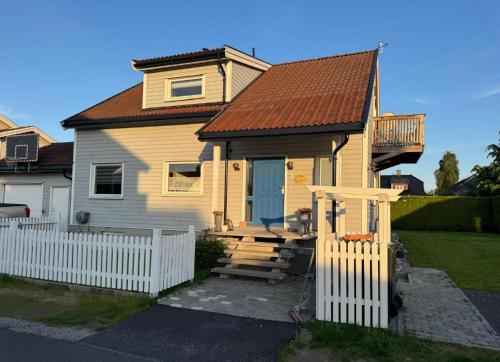 a small yellow house with a white fence at Hybel in Porsgrunn