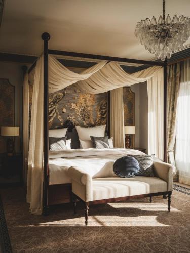 a bedroom with a canopy bed with a cat sleeping on it at Taj Hessischer Hof Frankfurt in Frankfurt