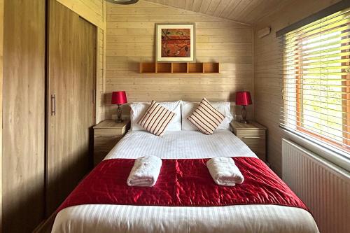 a bedroom with a large bed with red blanket at Lomond Woods Holiday Park in Balloch