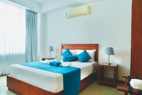 a bedroom with a large bed with blue pillows at Dreamwave Escape Nilaveli in Nilaveli