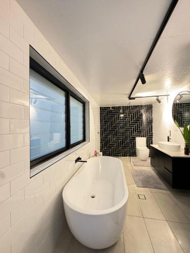a large white bath tub in a bathroom with a window at A spacious Family Retreat near the Beach in Cronulla
