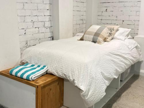 a bed with white sheets and pillows on a wooden platform at A spacious Family Retreat near the Beach in Cronulla