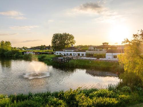 a fountain in the middle of a river with buildings at Drift Inn at Wyboston Lakes in Saint Neots