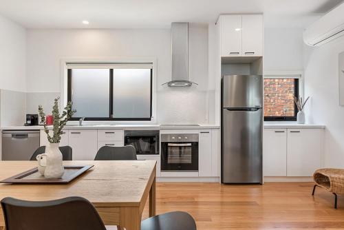 a kitchen with a table and a stainless steel refrigerator at Gorgeous 3-Bed House with Spacious Shared Backyard in Carnegie