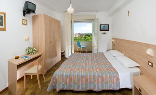 ein Hotelzimmer mit Bett, Schreibtisch und Fenster in der Unterkunft Hotel Gattuccio in Cesenatico