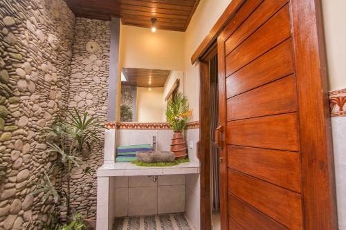 ein Badezimmer mit einem Waschbecken und einer Holztür in der Unterkunft Jagi Villa in Ubud
