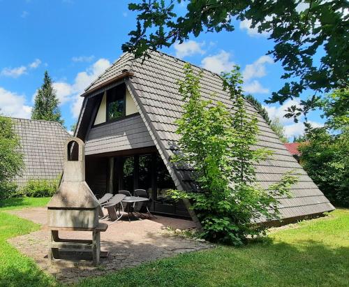 a house with a large roof with a bench in front of it at Ferienhaus Winnetou 114 in Waldbrunn