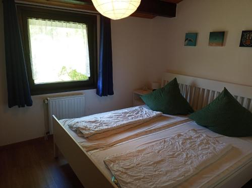 a bedroom with a bed with green pillows and a window at Ferienhaus Morgenrot in Waldbrunn