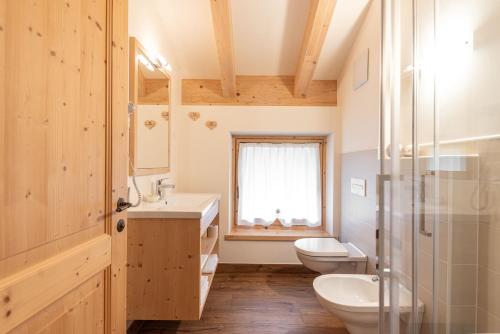 a bathroom with two sinks and a toilet and a window at Hotel Chalet Serena in Roncegno