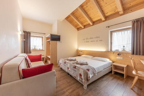 a bedroom with two beds and a couch and a tv at Hotel Chalet Serena in Roncegno