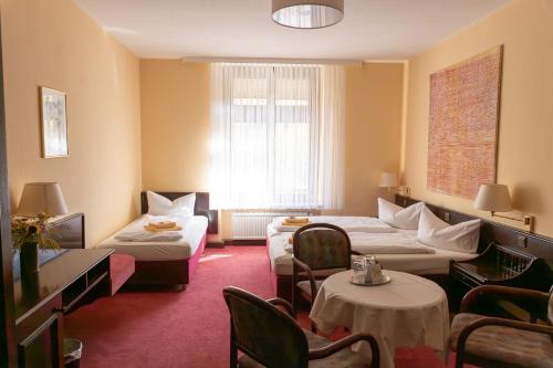 a hotel room with two beds and a couch at Hotel Marthahaus in Halle an der Saale