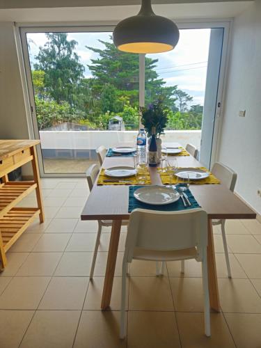 a dining room with a table and chairs and a large window at Residencias Requinte T3 Espacoso com Terraco e Vista in São Roque do Pico