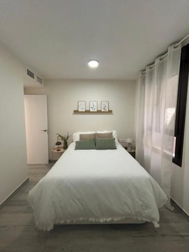 a bedroom with a large white bed and a window at Hernández Central Park in Melilla
