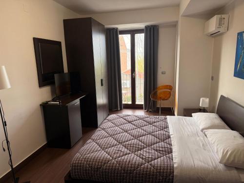 a bedroom with a bed and a television and a window at Nacional B&B in Monforte San Giorgio Marina