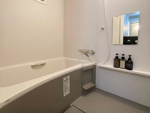 a bathroom with a tub with a mirror and a sink at Lapis Jogasaki B&B in Ito