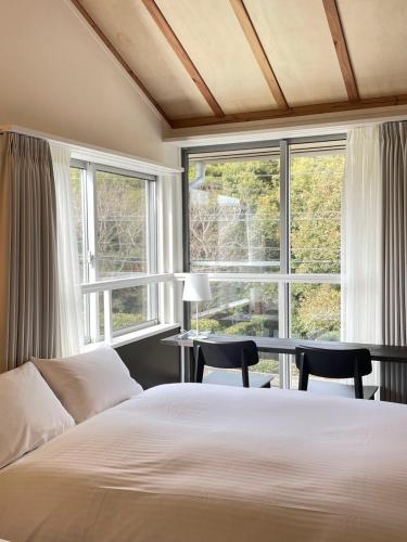 a bedroom with a large bed and two windows at Lapis Jogasaki B&B in Ito
