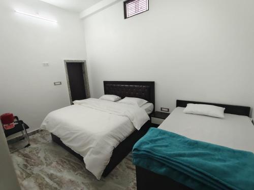 two beds in a room with white sheets at Ma SAVITRI PALACE in Ayodhya