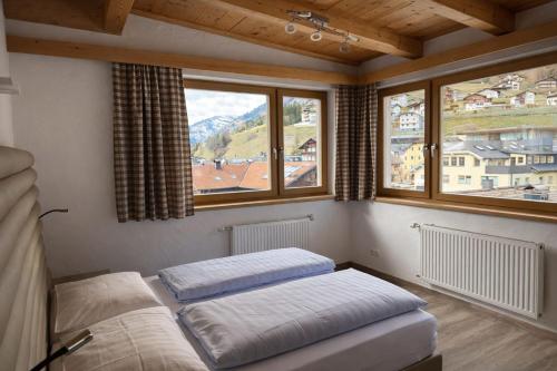 two beds in a room with two windows at Hotel Bergland in Sillian