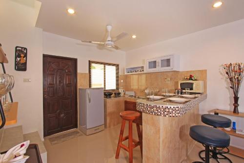 a kitchen with a counter with a refrigerator and stools at Soleil D'asie Residence in Chaweng Noi Beach