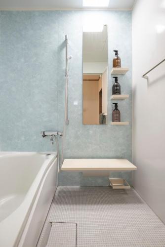 a bathroom with a tub and a mirror and a sink at Otaru Retro Villa in Otaru