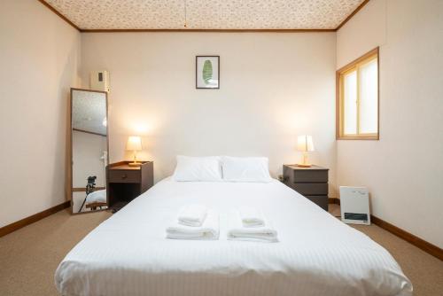 a bedroom with a large white bed with two lamps at Otaru Retro Villa in Otaru