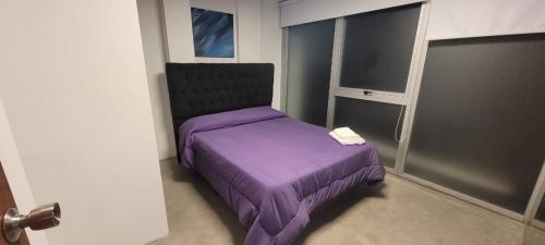 a bedroom with a purple bed with a book on it at DEPARTAMENTO moderno en Martinez cerca de clinicas y oficinas con WIFI y AA ideal para parejas y o viajes de trabajo in Martínez