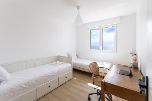 a room with a bed and a desk and a table at Nouveau - Horizons - Vue mer in Saint-Nazaire