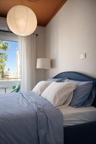 a bedroom with a bed with blue and white pillows at Top Location Studios - Avra, Boreio and Kyma in Larnaca