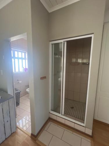 a bathroom with a glass shower in a room at Khans Residence in Gqeberha
