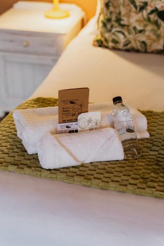 a basket with towels and a bottle of water on a bed at Greenfields Guesthouse & Restaurant in Alberton