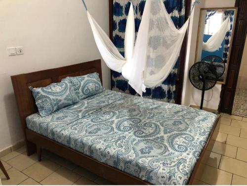a bed with a blue and white comforter in a bedroom at OCEAN-SI Mansion in Kribi