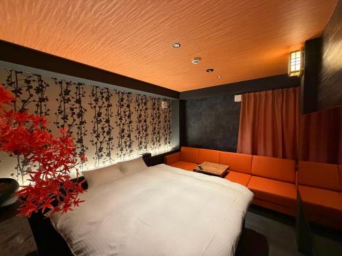 a bedroom with an orange couch and a white bed at Hatagoyorozu in Sasebo