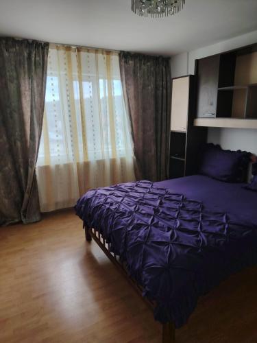 a bedroom with a purple bed and a window at Apartament in Geoagiu Băi