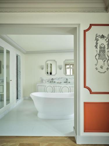 a white bathroom with a tub and a mirror at Hôtel Aventure in Paris